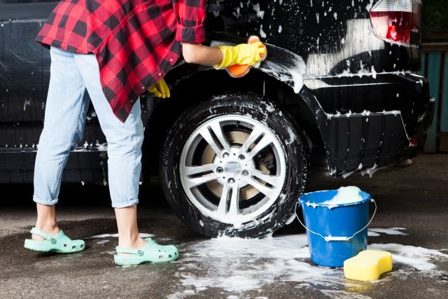 黒い車を洗車する女性