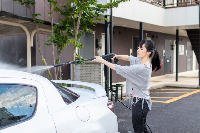 車を高圧洗浄機で洗浄する人物